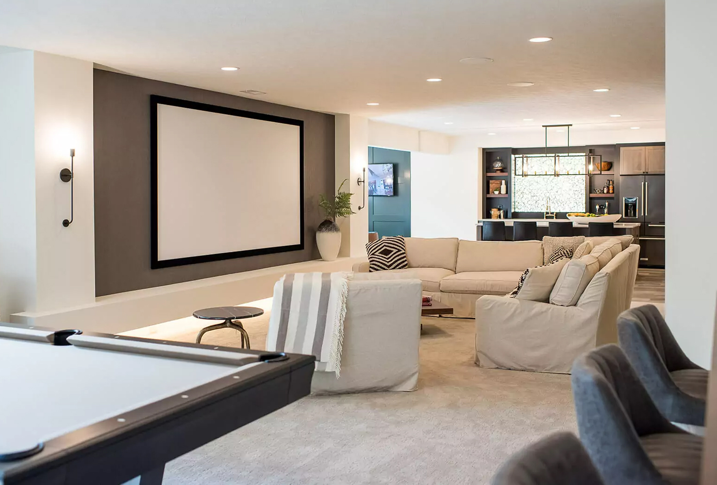 Finished basement with a full-screen tv and deep, sectional couch.